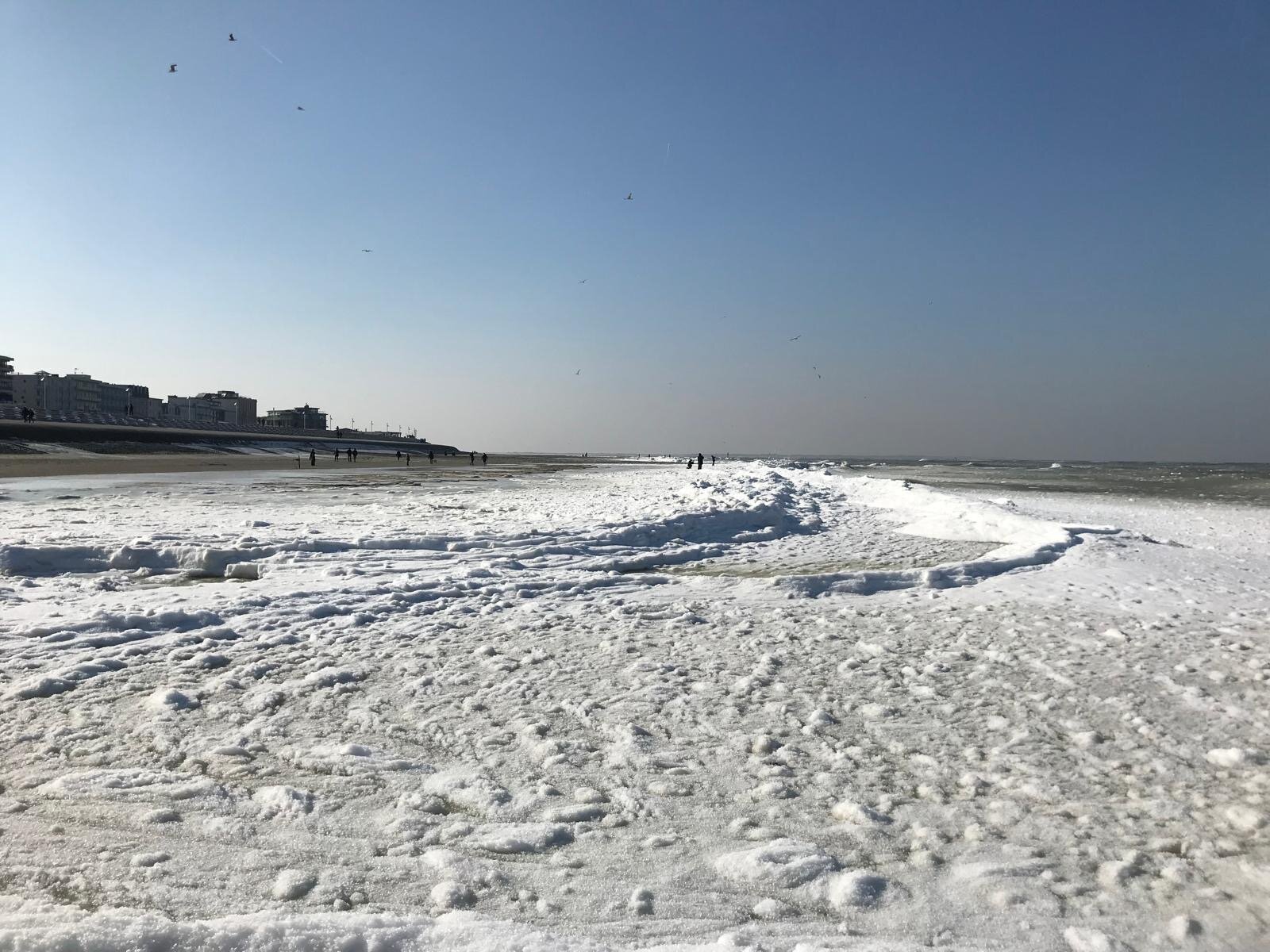 Meeresschaum am Strand mit Blick auf die Strandpromenade