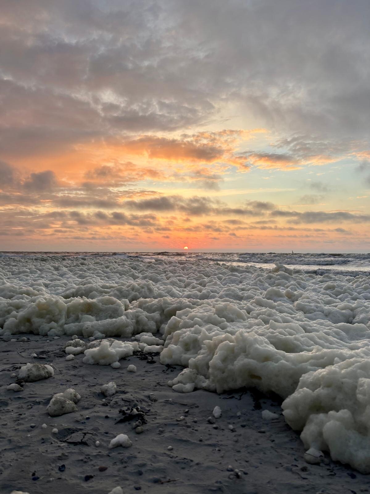 Sonnenuntergang hinter Meeresschaum am Strand