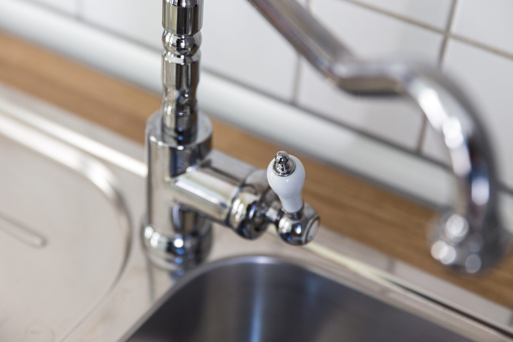 Detail des Wasserhahns mit Porzellangriff über der Spüle